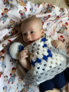 Baby holding crochetted blanket.