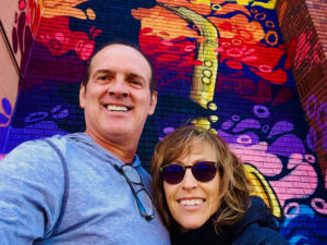Selfie in front of a colorful mural.